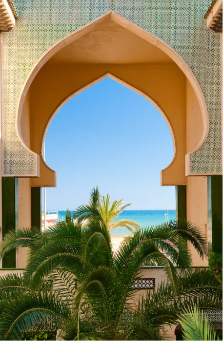 Carved Arabian arch framing palms and the sea